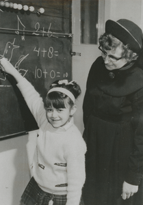 876939 Afbeelding van een meisje voor het schoolbord in een klaslokaal van de Piusschool voor R.K. onderwijs voor ...